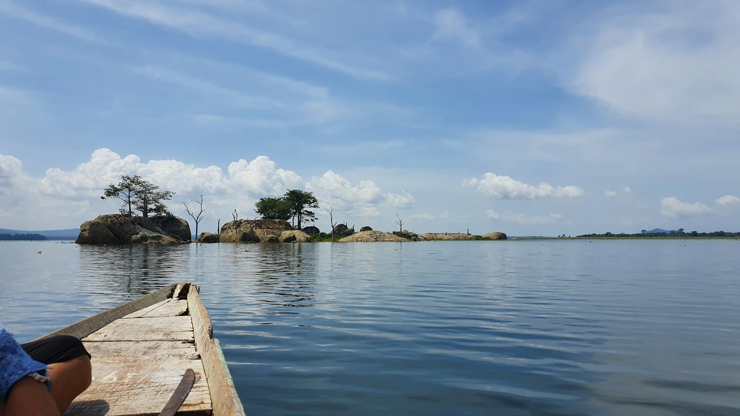 Sebuah perahu kayu menuju pulau-pulau berbatu dengan pepohonan hijau.